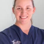 a woman in scrubs is smiling for the camera.