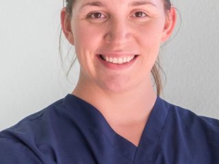 a woman in scrubs is smiling for the camera.