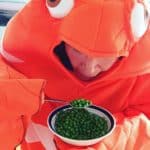 a man in an orange costume eating peas.
