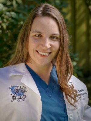 a woman in a white lab coat smiling.